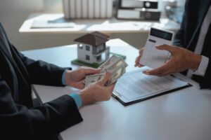Real estate agent discussing a contract while showing a calculator, as customer hands over cash for house purchase in an office setting