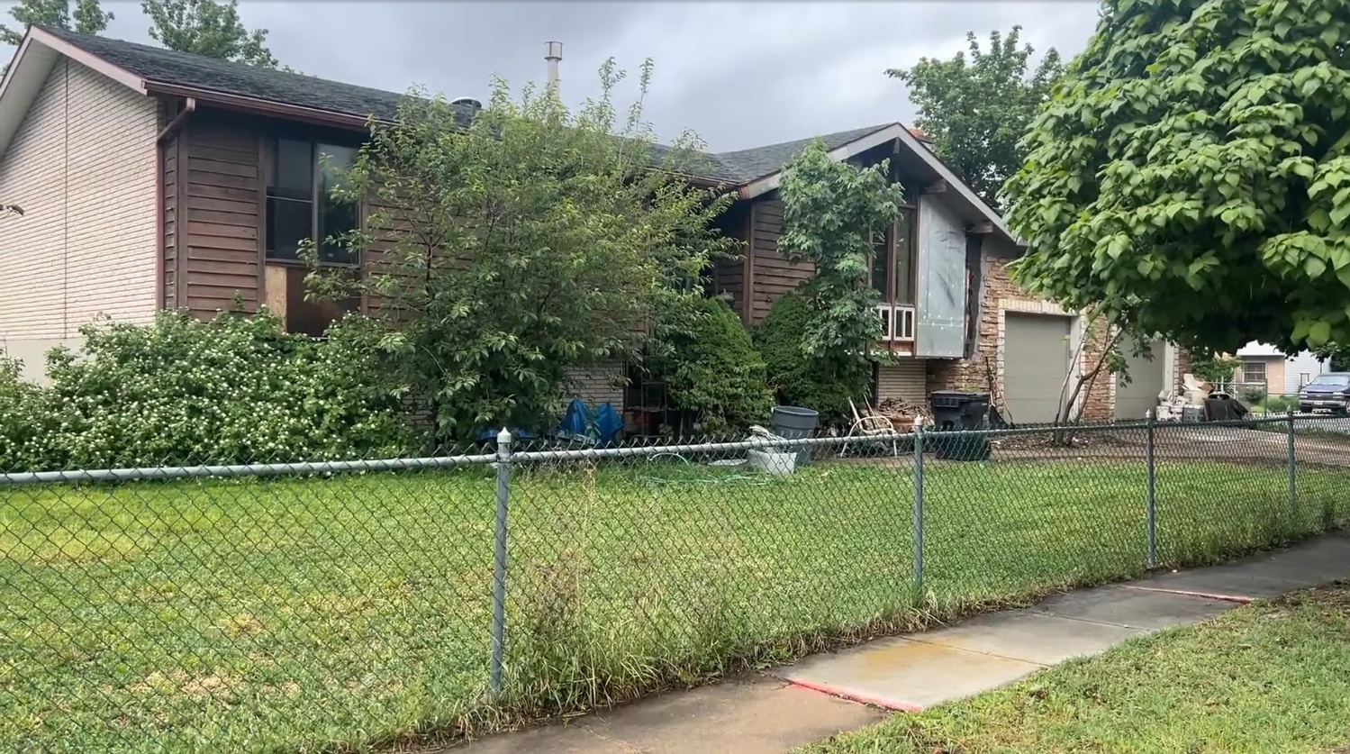 Older house with worn siding and overgrown shrubs, before renovation